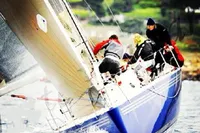 Sailors racing on a 1997 Custom IMS proto 33' yacht in dynamic waters.