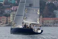 Sailboat "IMS proto 33'" from 1997 on calm waters near colorful coastal town.