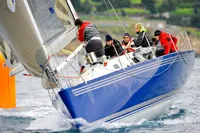 Sailors racing on a blue 1997 Custom IMS proto 33' yacht in dynamic waters.