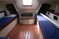 Interior of 1997 Custom IMS proto 33' sailboat with wooden flooring and blue seating.