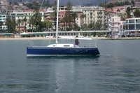 Sailboat "IMS proto 33'" 1997 model on calm water near coastal town.
