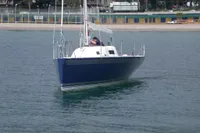 Sleek 1997 Custom IMS proto 33' sailboat on calm water near a beach.