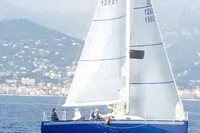 Sailboat "IMS proto 33'" from 1997 on calm sea with mountainous backdrop.