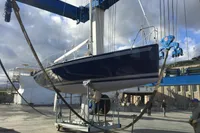 Sailboat "IMS proto 33'" 1997 model being lifted by crane in a shipyard.