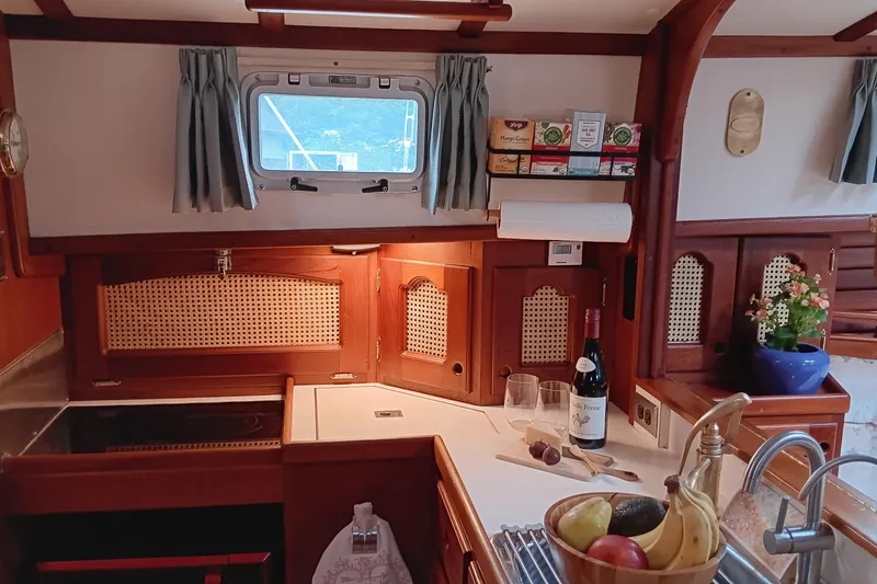 Rhythm Yacht Photos Pics Cozy 1991 Gozzard 31 yacht kitchen with wooden cabinetry, fruit bowl, and wine bottle.