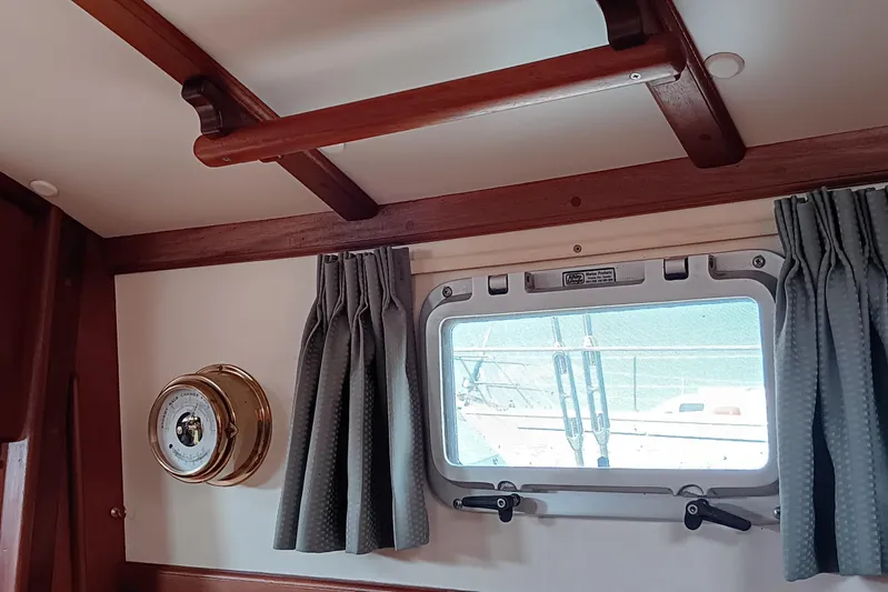 Rhythm Yacht Photos Pics Interior of 1991 Gozzard 31 sailboat with porthole, curtains, and brass barometer.