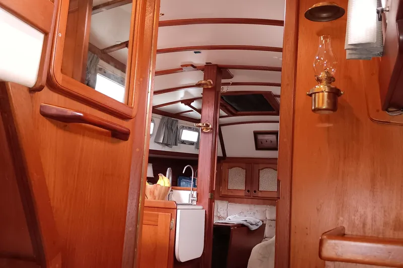 Rhythm Yacht Photos Pics Interior of a 1991 Gozzard 31 sailboat, featuring wooden cabinetry and cozy seating.