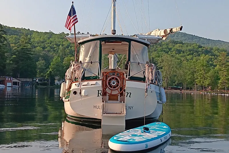 Rhythm Yacht Photos Pics Sailboat Gozzard 31 (1991) with paddleboard on calm lake, surrounded by lush greenery.