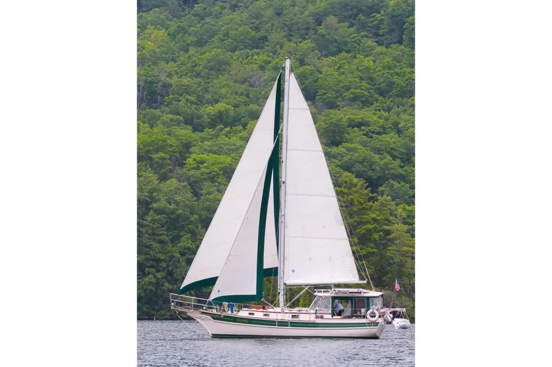 Rhythm Yacht Photos Pics Sailboat Gozzard 31 (1991) on calm water with lush green forest backdrop.