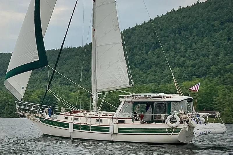 Rhythm Yacht Photos Pics Sailing yacht Gozzard 31 from 1991 on a serene lake with forested hills.