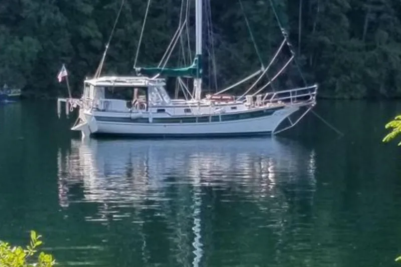 Rhythm Yacht Photos Pics Sailboat Gozzard 31 (1991) anchored on a serene lake surrounded by lush forest.
