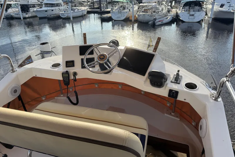  Yacht Photos Pics 2024 Ranger Tugs R31CB helm with steering wheel, controls, and marina view.