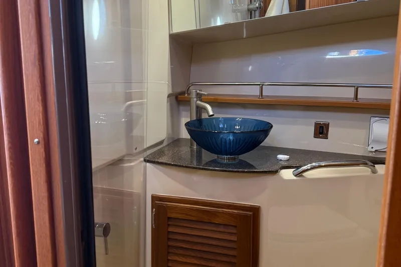  Yacht Photos Pics 2024 Ranger Tugs R31CB bathroom with elegant blue glass sink and modern fixtures.