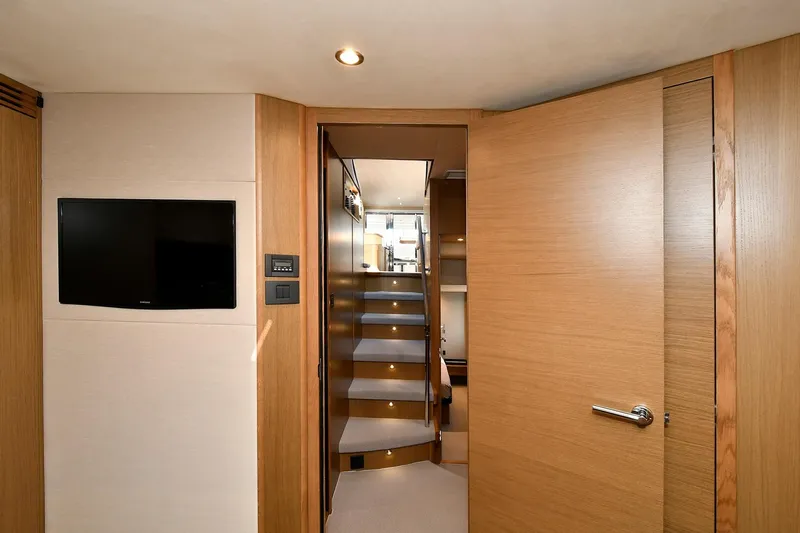 "about Time" Yacht Photos Pics Interior of 2016 Princess 52 Flybridge Yacht with wooden stairs and wall-mounted TV.