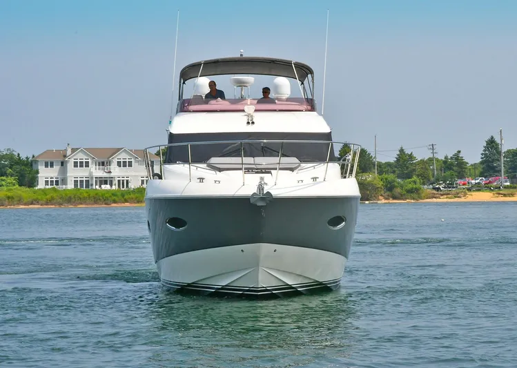 "about Time" Yacht Photos Pics 2016 Princess 52 Flybridge Yacht cruising on calm waters near shoreline homes.