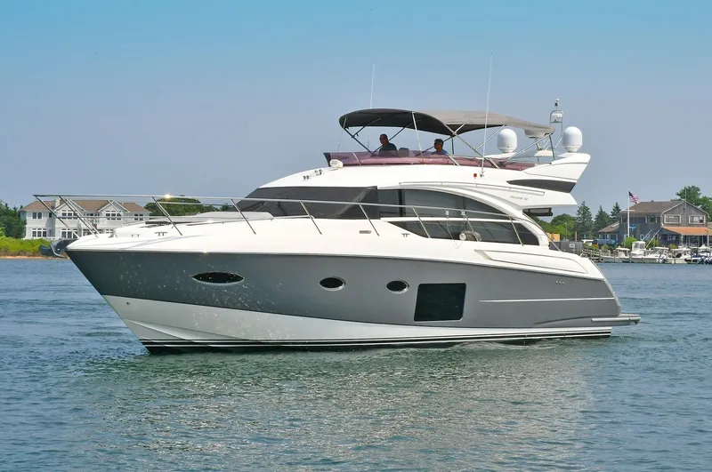 "about Time" Yacht Photos Pics 2016 Princess 52 Flybridge Yacht cruising on calm waters near coastal homes.