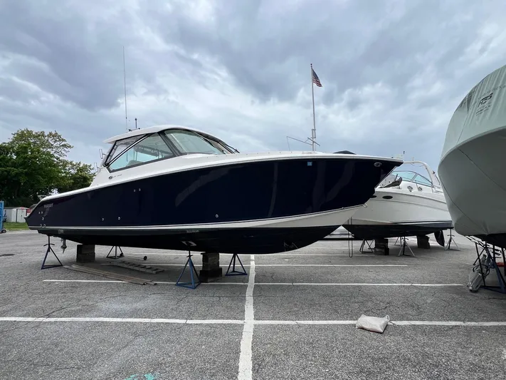 Hot Pursuit Yacht Photos Pics 2016 Pursuit 325 DC boat on stands in a parking lot under cloudy skies.