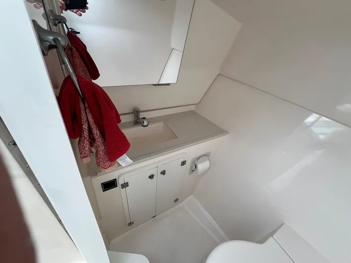 Hot Pursuit Yacht Photos Pics Compact bathroom in a 2016 Pursuit 325 DC boat, featuring sink and red towels.