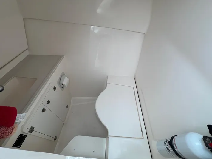 Hot Pursuit Yacht Photos Pics Interior of 2016 Pursuit 325 DC boat, featuring a compact bathroom with storage and fire extinguisher.