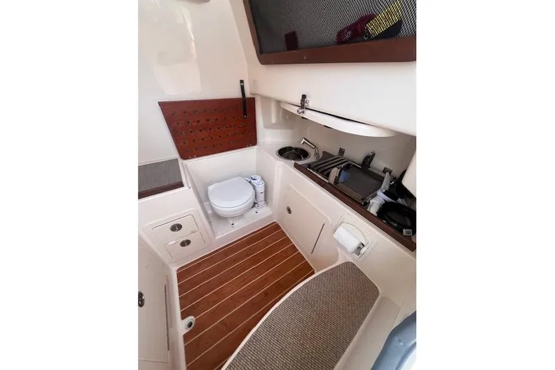  Yacht Photos Pics 2023 Grady-White Canyon 306 boat interior with toilet, sink, and wooden flooring.