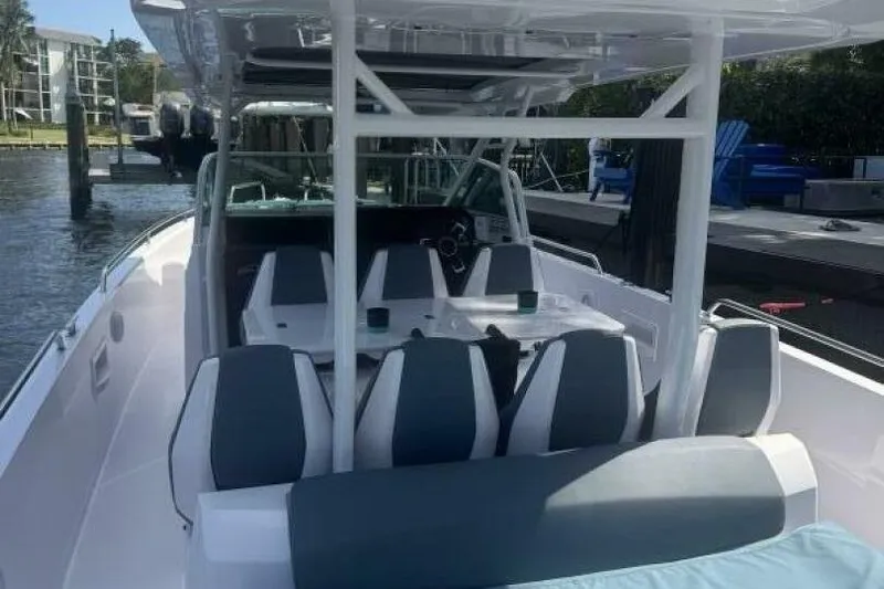 Milan Yacht Photos Pics 2024 Axopar 37 Sun Top boat interior with seating and table, docked by the water.