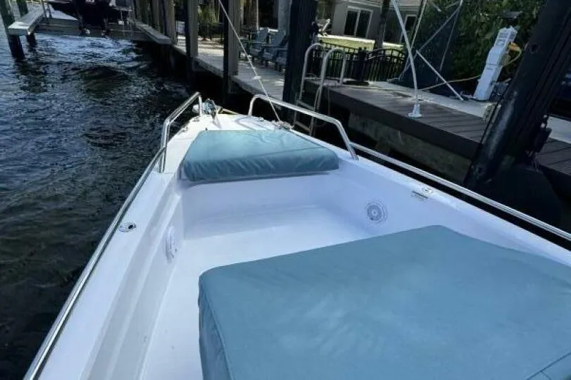 Milan Yacht Photos Pics 2024 Axopar 37 Sun Top boat with cushioned seating, docked by the water.