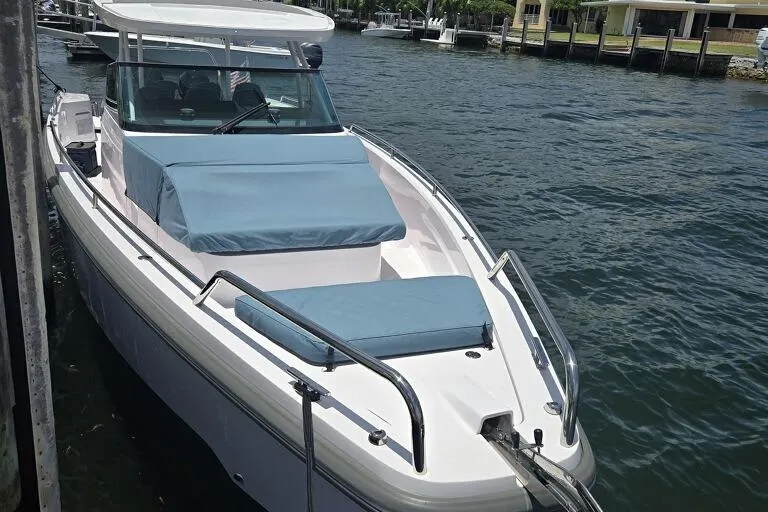 Milan Yacht Photos Pics 2024 Axopar 37 Sun Top boat docked on calm water, featuring sleek design and blue seating.