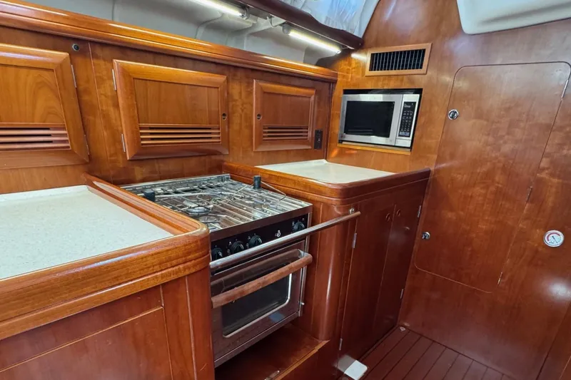 Sanctuary Yacht Photos Pics Luxurious 2005 Beneteau 473 yacht kitchen with wood cabinetry, stove, and microwave.