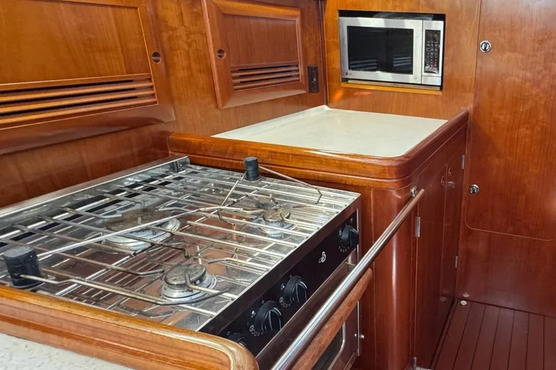 Sanctuary Yacht Photos Pics Luxurious 2005 Beneteau 473 yacht kitchen with stove and microwave, featuring elegant wood cabinetry.