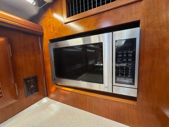 Sanctuary Yacht Photos Pics Microwave in 2005 Beneteau Oceanis Clipper 473 yacht kitchen, set in wooden cabinetry.