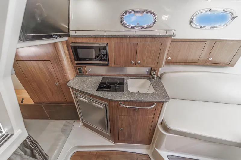 Slingshot Yacht Photos Pics 2018 Boston Whaler 315 Conquest interior kitchen with microwave, sink, and wooden cabinetry.