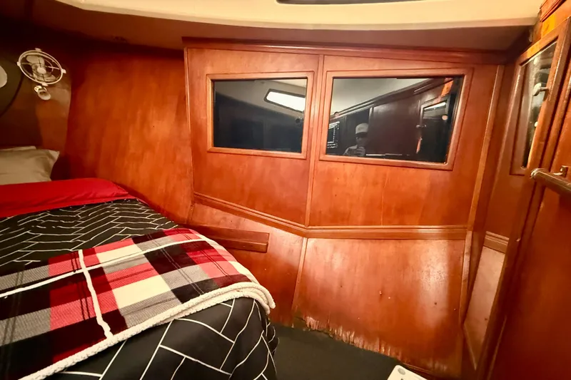  Yacht Photos Pics Cozy cabin interior of a 1994 Custom 60 Trawler with wood paneling and plaid bedding.