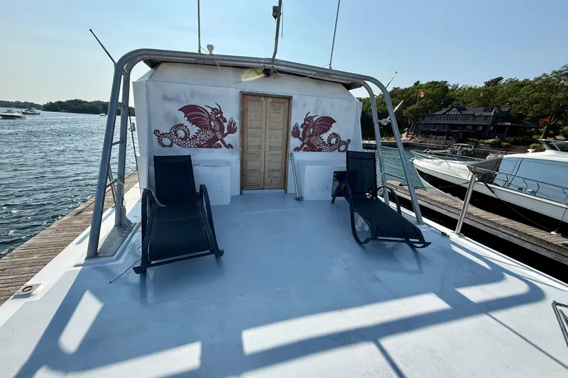  Yacht Photos Pics Custom 60 Trawler 1994 with dragon artwork, deck chairs, docked by scenic waterfront.