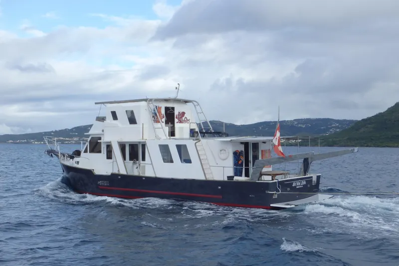  Yacht Photos Pics Custom 1994 60 Trawler cruising on the ocean near lush green hills.