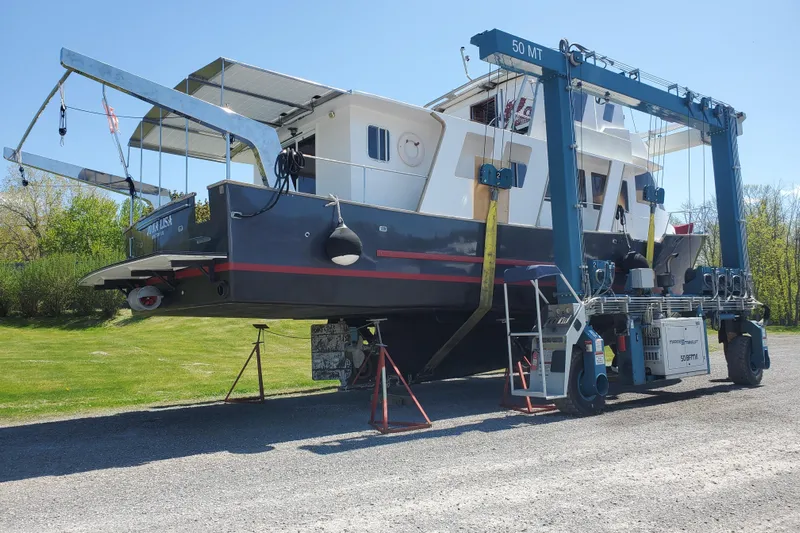  Yacht Photos Pics Custom 1994 60 Trawler on a lift for maintenance, surrounded by greenery.