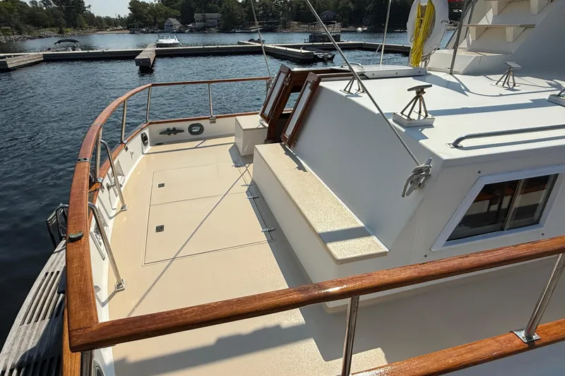  Yacht Photos Pics 1990 Grand Banks 42 Classic yacht deck with wooden railings, docked by a serene lake.