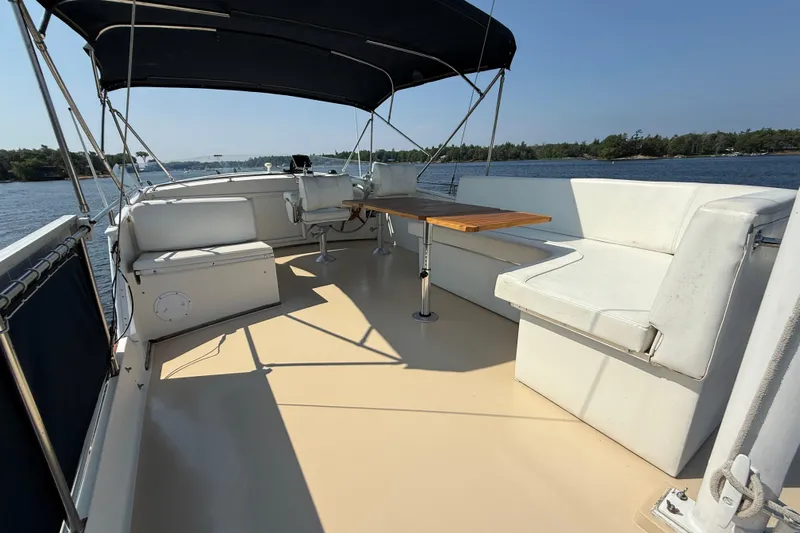  Yacht Photos Pics 1990 Grand Banks 42 Classic yacht deck with seating and table, under a canopy, on calm waters.