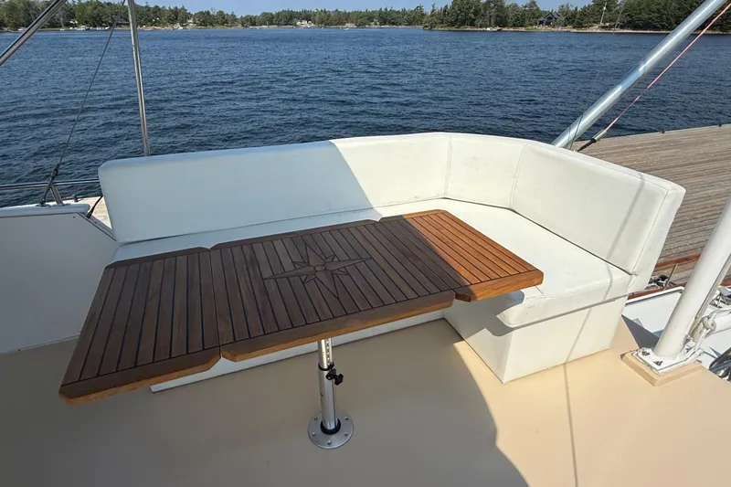  Yacht Photos Pics Grand Banks 42 Classic 1990 yacht with wooden table and white seating, overlooking serene water.