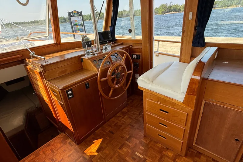  Yacht Photos Pics 1990 Grand Banks 42 Classic boat interior with wooden helm and cushioned seating.