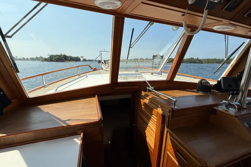  Yacht Photos Pics Interior view of 1990 Grand Banks 42 Classic yacht, showcasing wooden helm and scenic waterway.