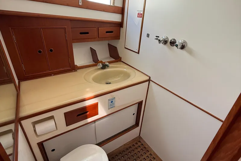  Yacht Photos Pics Bathroom interior of 1990 Grand Banks 42 Classic yacht with wooden cabinetry and beige sink.