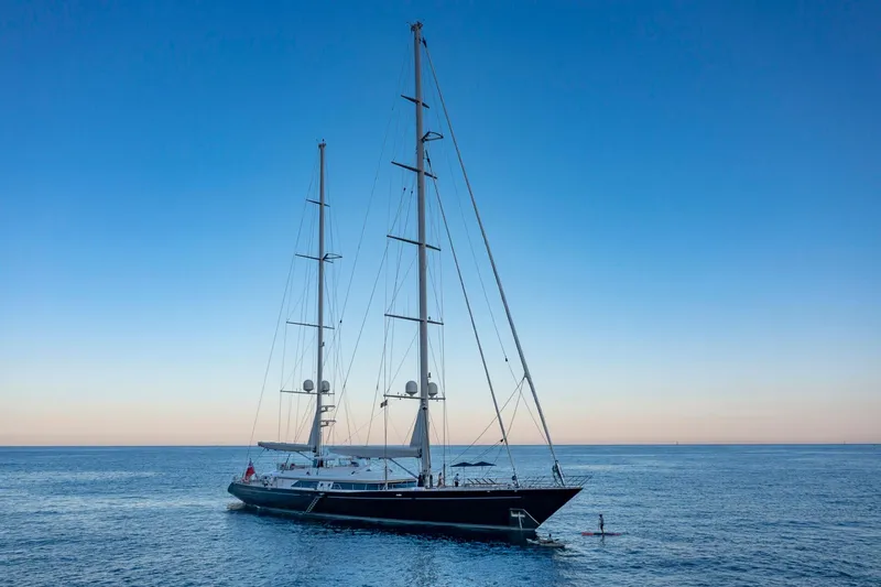 Zenji Yacht Photos Pics Luxury Perini Navi 56m yacht from 2004 sailing at sunset on calm ocean waters.