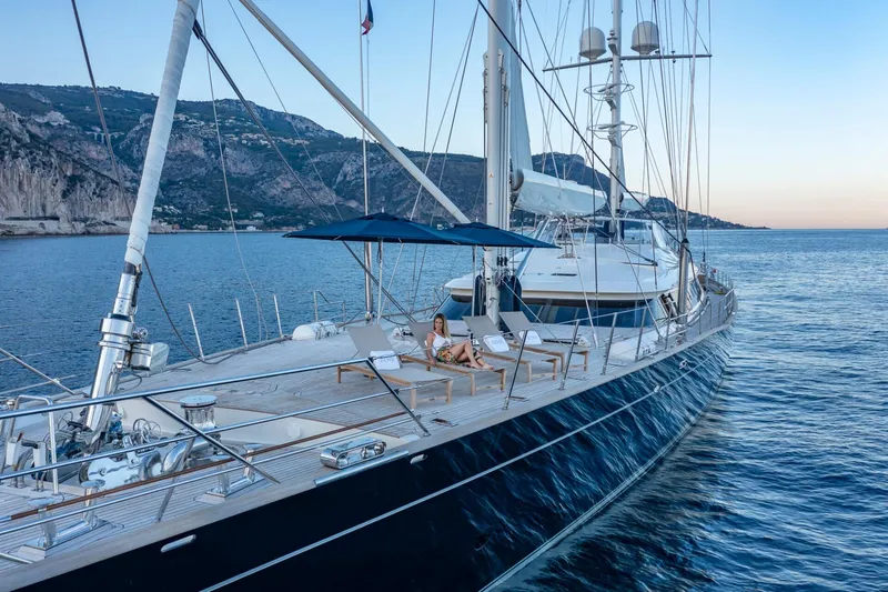 Zenji Yacht Photos Pics Luxurious 2004 Perini Navi 56m yacht sailing near scenic coastal cliffs.