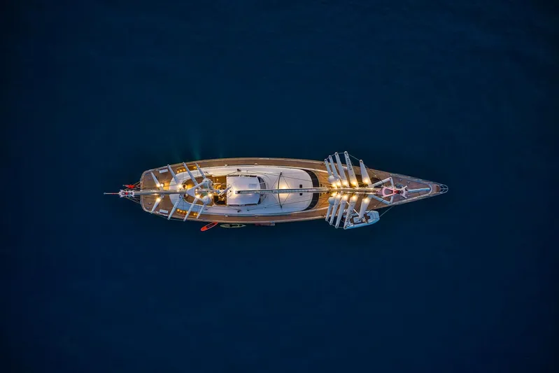 Zenji Yacht Photos Pics Aerial view of illuminated 2004 Perini Navi 56m yacht on dark blue water.