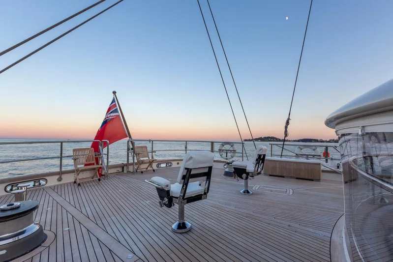 Zenji Yacht Photos Pics Deck of 2004 Perini Navi 56m yacht at sunset, featuring chairs and a flag.