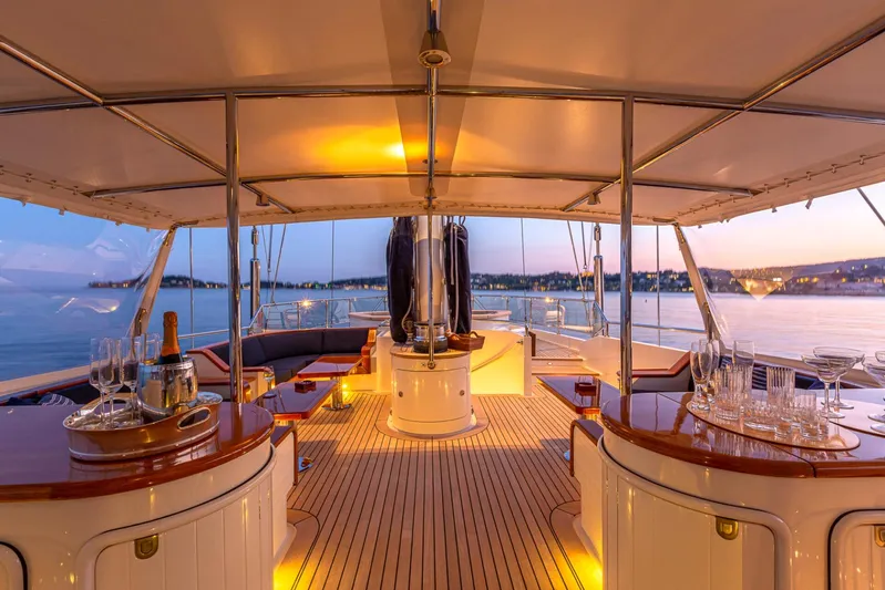 Zenji Yacht Photos Pics Luxurious 2004 Perini Navi 56m yacht deck at sunset, featuring elegant seating and dining area.