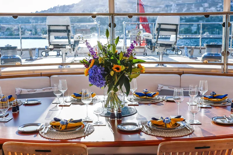 Zenji Yacht Photos Pics Elegant dining setup on 2004 Perini Navi 56m yacht, featuring floral centerpiece and ocean view.