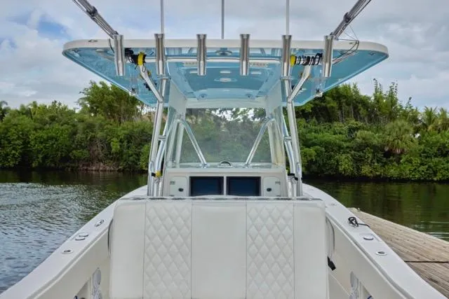  Yacht Photos Pics 2015 Invincible 36 boat with T-top, docked near lush greenery.