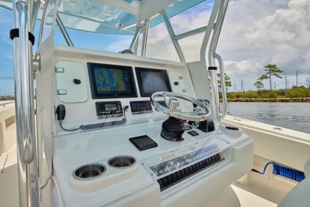  Yacht Photos Pics 2015 Invincible 36 boat dashboard with navigation screens and steering wheel on a sunny day.