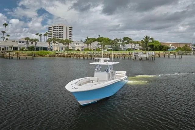  Yacht Photos Pics 2015 Invincible 36 boat cruising near a coastal town under cloudy skies.